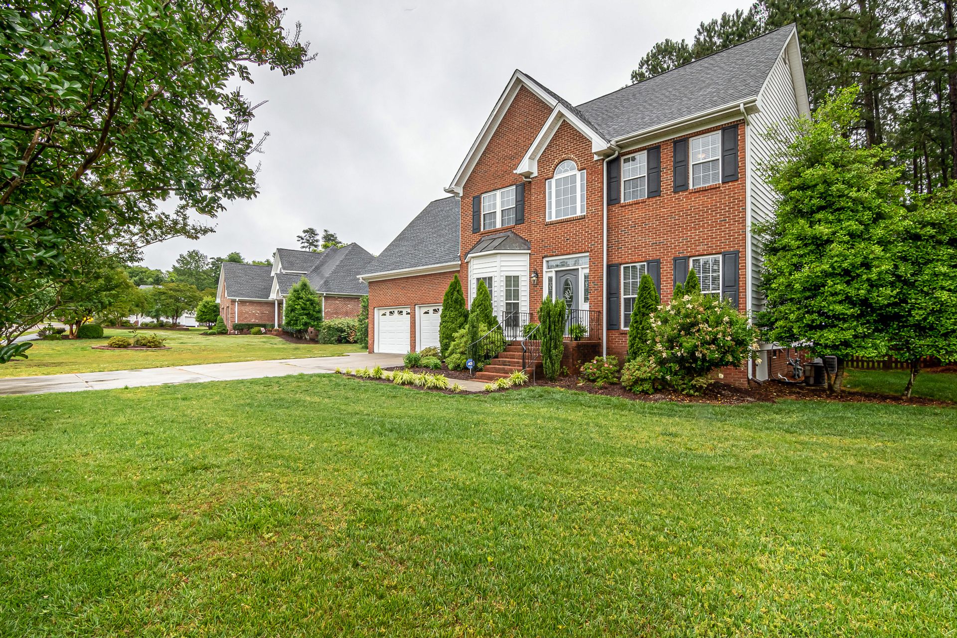 Well-kept green front lawn of a suburban brick home with a clean driveway
